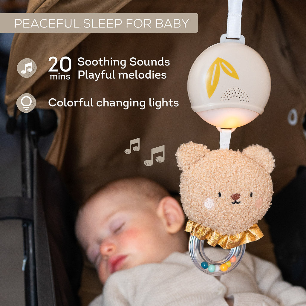 Baby sleeping peacefully in a stroller under the Taf Toys light up musical bear playing soothing sounds and melodies
