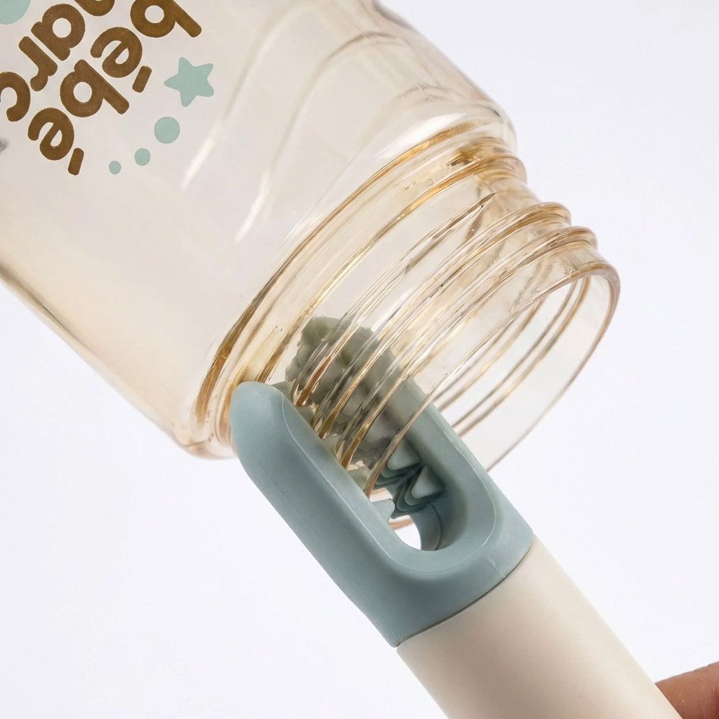 Close-up of flexible silicone teeth cleaning milk residue from the screw threads and mouth rim of a baby bottle.