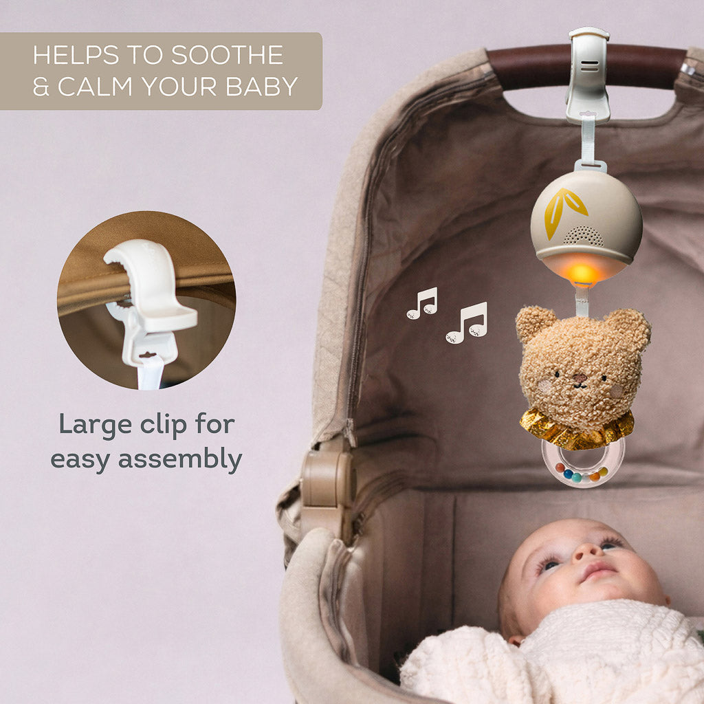 Close-up view of the extra-large attachment clip of the Taf Toys soothing bear fastened securely to a pram canopy above a baby