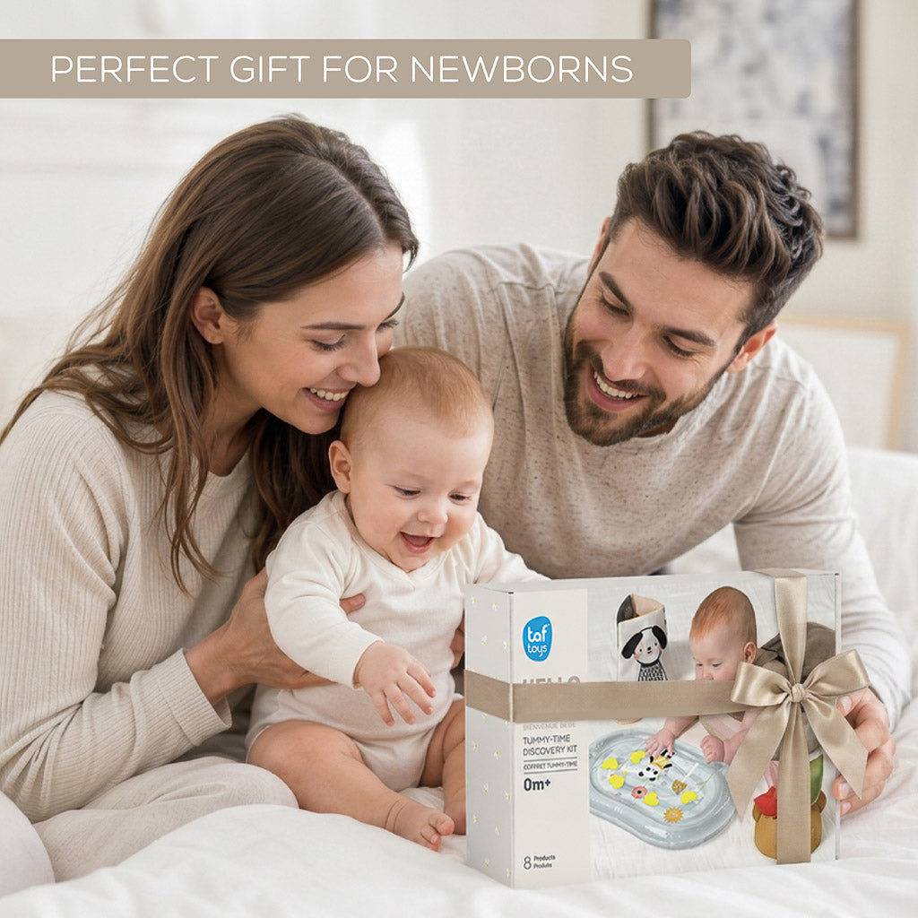 Parents with baby presenting ribbon-wrapped Taf Toys Tummy-Time Discovery Kit box as a gift for newborns